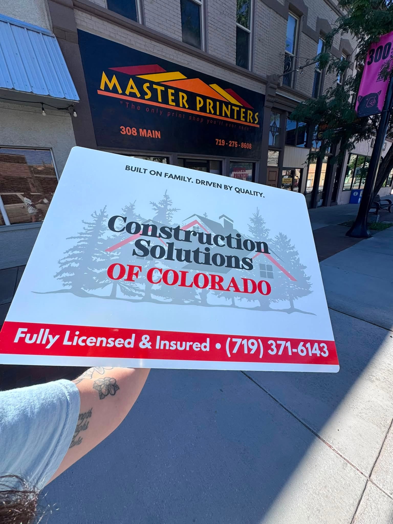 Construction Solutions of Colorado yard sign held outside Master Printers in Canon City